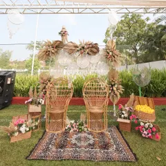 We designed this special seating for the couple, featuring rustic rattan peacock chairs on a patterned rug. The backdrop of woven plates, dreamcatchers, and dried florals completes the bohemian aesthetic for a Haldi or Mehndi ceremony.