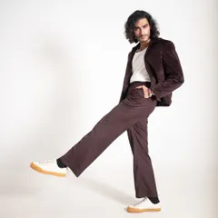 A playful studio shot of Vishak Nair in a brown velvet suit paired with casual sneakers. This demonstrates how to dress down a suit for a more modern, relaxed feel.
