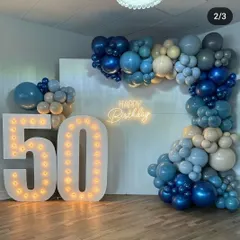 This image shows the balance of the 50th birthday setup, highlighting how the marquee numbers and the L-shaped balloon garland frame the space. The color gradient in the balloons adds visual depth.