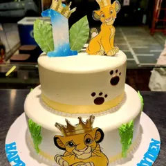 A majestic two-tier Lion King cake for a royal first birthday. This design features beloved characters like Simba, paw prints, and jungle leaves, perfect for a fan of the classic Disney movie.