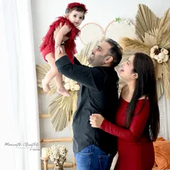 Pure joy as dad lifts his baby girl high. This beautiful family portrait, set against a warm boho backdrop, captures the playful and loving connection between parents and their child.