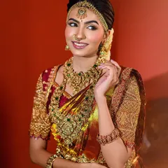 A signature Muhurtham look, glowing with warmth and tradition. The heavy gold jewelry and richly embroidered saree are captured in their full glory, making for a perfect South Indian bridal portrait.
