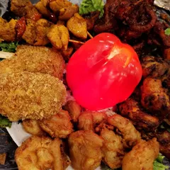 A mouth-watering close-up of a mixed starter platter, featuring crumb-fried cutlets, chicken tikka, and golden-fried prawns.