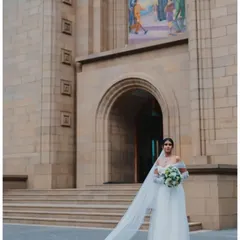 A breathtaking portrait of the bride in her magnificent white gown with a long, flowing veil, standing before the grand church, a truly epic wedding photograph.