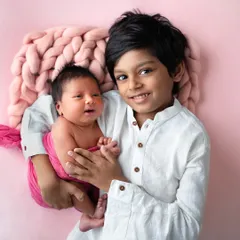 A proud big brother holds his three-week-new baby sister. The bond between siblings is so special, and capturing these early moments of love and protection is priceless.