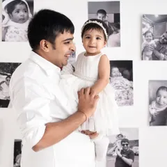 A proud father holds his daughter, surrounded by pictures that tell their family's story.