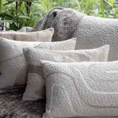 Handcrafted textured cushions in a warm sandstone palette. Wrapped in ultra-soft bouclé fabric with abstract embroidery, they offer a plush, cozy feel that invites you to unwind.