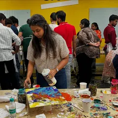 A participant fully engaged in a fluid art workshop with GoTo Technologies. It's all about pouring colors and watching them blend into a one-of-a-kind abstract piece.