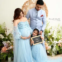 A family portrait filled with anticipation. The older sibling holds a "Big Sister" sign, proudly announcing her new role. These are the moments that build the story of your growing family.