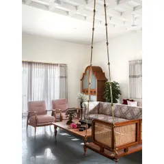 Behind the courtyard is the living room, a modest yet elegant space featuring the quintessential Indian swing. All-teak furniture provides warmth, a patterned fabric on the sofa adds ethnic appeal, and the coffered ceiling brings the space together into a cozy haven.