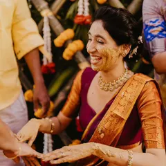 A candid moment from a Telugu Haldi ceremony, capturing the bride's joyous laughter against a traditional bamboo and marigold backdrop.