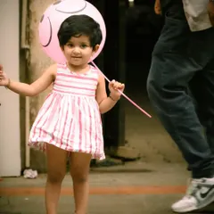 The pure innocence of a child with her balloon. I captured this little girl in a candid moment on the street, using a soft focus on the background to make her and her happy expression the center of attention.