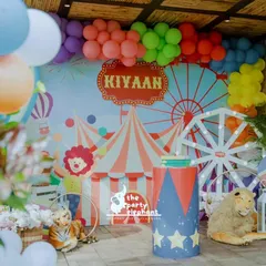 Step right up to a whimsical carnival birthday. This vibrant backdrop features a custom circus tent and ferris wheel design, framed by a colorful balloon garland and playful animal props, setting the stage for a day of fun and games.
