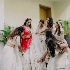A sweet, candid moment as the bride's friends help her with her lehenga, a beautiful interaction before she meets her groom.