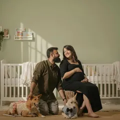 Your whole family is welcome, even the furry members! This is a heartwarming family maternity portrait in my studio's nursery setup, complete with a crib and soft, natural lighting.