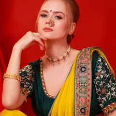 A stunning festive portrait against a rich red background. The model's traditional attire, complete with a nath and bindi, is vibrant and captures a celebratory mood.