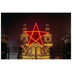 A giant, illuminated red star hangs over the entrance to the Sacred Heart Cathedral in New Delhi during Christmas. The foggy night and warm lights create a magical and festive atmosphere.