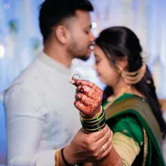 The groom holds the bride's hand, showing off her engagement ring. This shot beautifully captures the detail of the ring and the henna on her hand, with the couple in a soft, romantic embrace.