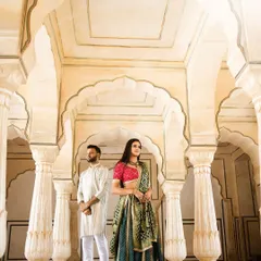 An elegant portrait of a couple standing between the majestic pillars and arches of a Jaipur palace, showcasing the grandeur of the location.