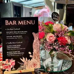 A close-up of the custom-designed bar menu, which includes themed cocktail names. This detail, paired with a floral centerpiece in a martini glass, showcases the thoughtful personalization I bring to every event.