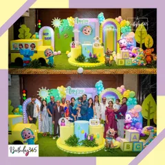 The birthday girl and her family pose for a picture in front of the Cocomelon-themed stage, complete with a large school bus prop and character cutouts.
