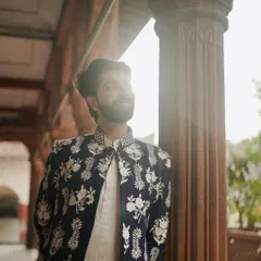 A sun-kissed shot highlighting the exquisite white floral embroidery on our navy Nehru jacket. It's a piece that feels both timeless and romantic.