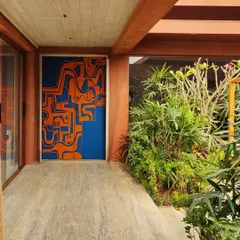 This artistic door is seen here as the main entrance, set against the home's earthy exterior and lush greenery. It serves as a bold, abstract monolith that immediately signals a space where art and life intertwine.