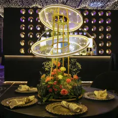 A modern, illuminated centerpiece featuring floral arrangements within glowing rings. This custom piece is an example of how we integrate lighting directly into our decor for a futuristic and polished look.