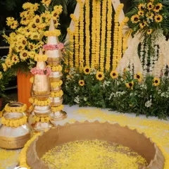 A close-up of the traditional elements. I stacked and decorated brass matkas with marigold garlands and pink flowers, placed next to a large vessel filled with turmeric-colored water and petals for the ceremony.