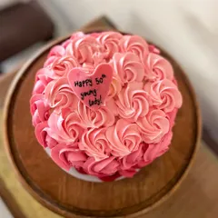 A beautiful cake featuring pink ombre buttercream rosettes. This design is perfect for birthdays and anniversaries, with a little heart plaque that reads "Happy 50th young lady!"
