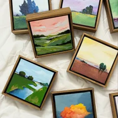 A selection of my miniature landscape paintings. These small, framed canvases capture fleeting moments in nature, from rolling hills under a pink sky to a single tree against a dramatic, cloudy backdrop.