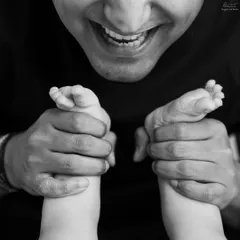 A father's smile and his baby's tiny feet. This unique angle in black and white creates an artistic and emotional portrait of their connection.