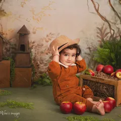 An autumn adventure in the studio. This little one is dressed for apple picking, sitting in a rustic, woodland-themed set complete with a crate of apples and a tiny birdhouse.
