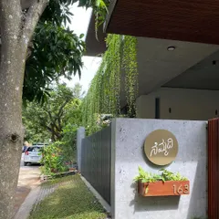 The name of the house, "Nemmadi" (meaning peace or tranquility in Kannada), is displayed on a simple, elegant nameplate against a board-formed concrete wall, reflecting the home's core philosophy.