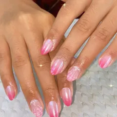 A soft and dreamy pink ombre. This manicure features a beautiful gradient from a sheer, natural pink to a vibrant, shimmery pink at the tips, with delicate seashell-like accents.