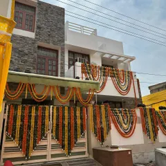 A beautiful home exterior decorated for a wedding, using traditional marigold garlands in scalloped designs across the balconies and entrance gate.