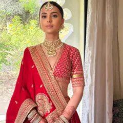 A portrait of bridal elegance. The makeup is kept soft and minimal to let the bride's natural beauty and the magnificent red Sabyasachi lehenga take center stage.