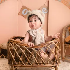 This little one is sitting in a rattan bassinet, dressed as a little bear, creating a super cute and whimsical portrait.