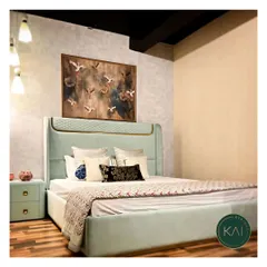 This bespoke bed in a soft mint green fabric features a beautifully curved, quilted headboard and gold-finished trim. It's a centerpiece designed to bring a sense of calm and luxury to the bedroom.