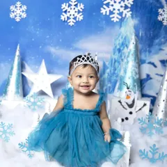 A magical Frozen-themed photoshoot for a slightly older baby. She is dressed as a snow princess, smiling in a winter wonderland complete with ice castles, snowflakes, and a friendly Olaf.