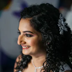 A close-up of this curly-haired bride's joyful smile. The makeup is designed to complement her features and let her natural beauty shine.