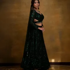 A full-length view of the stunning emerald green sequin lehenga. The complete look, including makeup, hair, and styling, creates a cohesive and breathtaking appearance.
