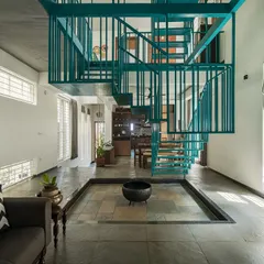 A staircase should be more than just a utility; it can be the heart of a home. This suspended metallic staircase in 'Jodi Mane' is a functional sculpture, adding a bold splash of color and creating dynamic shadow play from the ample daylight.