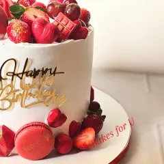 A closer look at the details on the red-themed birthday cake. You can see the fresh strawberries, geometric chocolate hearts, and a hint of gold dust on the macaron.