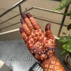 A classic engagement mehendi for the palm, featuring the couple's initials intertwined within a traditional circular pattern, symbolizing their union.
