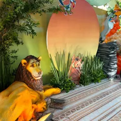 A closer look at the Pride Lands backdrop, featuring a large prop of Mufasa, a Pumbaa cutout, and Zazu perched atop the iconic sunset. I use strategic lighting to make the characters and scenery pop.