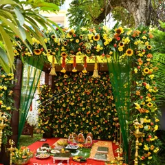 We specialize in creating beautiful outdoor settings for traditional ceremonies. This pooja mandap features a dense wall of sunflowers and marigolds, framed by a lush floral arch, perfect for housewarmings or naming ceremonies.