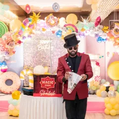 A newspaper trick in front of a colorful candyland backdrop. The vibrant theme of this party made the classic illusions even more visually exciting.