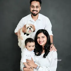 A formal studio portrait of a family, including their pet dog wearing a bow tie. This image is a great example of a classic family photo that includes every member.