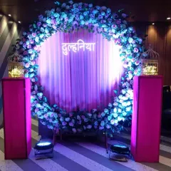 A beautiful circular floral gate for a "Dulhania" welcome party. The purple and blue flowers, combined with dramatic lighting, create a perfect entrance or photo booth.